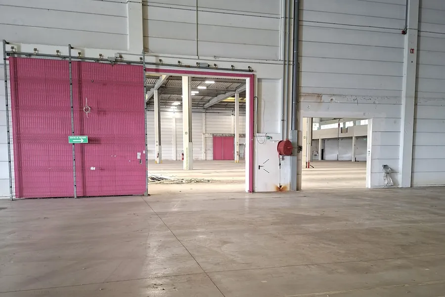 Porte coulissante coupe-feu rose sur un mur séparatif de cellules d'entrepôt